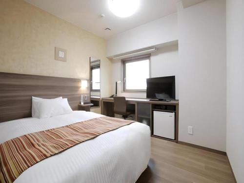 a bedroom with a bed and a desk with a television at Hotel Sunoak Kashiwanoha in Kashiwa