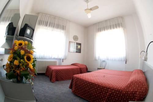a hotel room with two beds and a vase of flowers at Hotel Milano in Pistoia