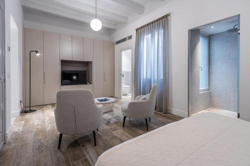 a bedroom with a bed and two chairs and a television at Old Theatre Suites - Panarea in Valletta