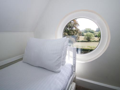 a bedroom with a bed and an oval window at The Old Vicarage in Leominster