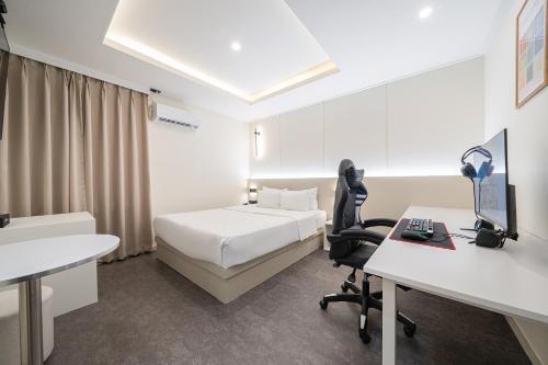 a bedroom with a bed and a desk with a computer at No25 Hotel Songnae Station in Bucheon