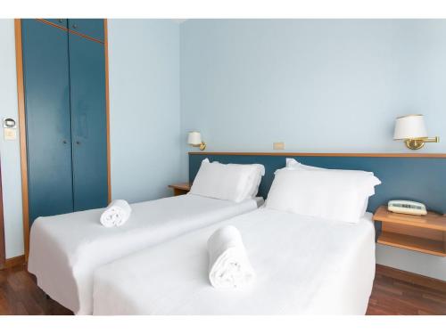 two beds in a room with white sheets and towels at B&B HOTEL Riviera Celle Ligure in Celle Ligure