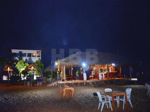 a group of tables and chairs on a beach at night at Harmony Beach Bangalow in Tangalle