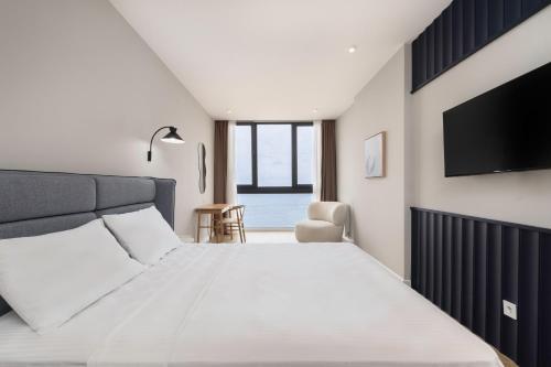 a bedroom with a large bed and a flat screen tv at Next White Aparthotel OFFICIAL in Batumi