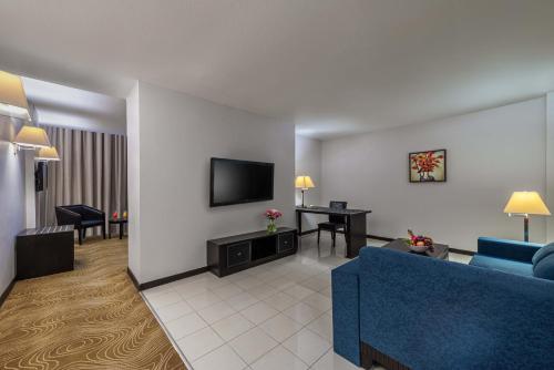 a living room with a blue couch and a tv at Razana Hotel Al Jubail in Al Jubayl