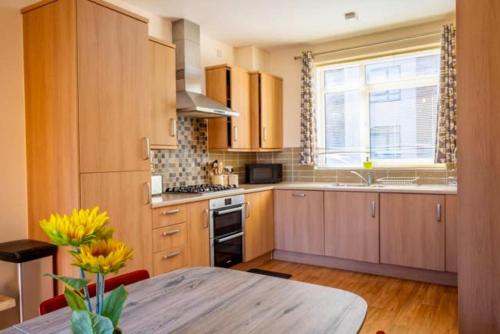 a kitchen with wooden cabinets and a table and a window at Posh Wetheringsett in Milton Keynes in Milton Keynes