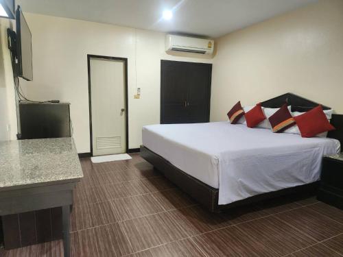 a bedroom with a large white bed with red pillows at Amorn Inn Resort in Chiang Rai