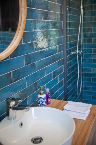 a bathroom with a sink and a mirror and blue tiles at Manoir d Armagnac in Courrensan