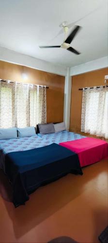 a bedroom with a large bed with a red and blue blanket at Tejana villa in Mananthavady
