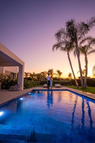 a man and a woman standing next to a swimming pool at TAF Villas Beach Resort with Tesla in Tigaki