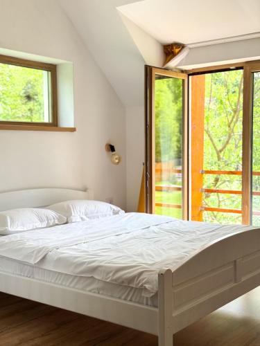 a bedroom with a white bed and a window at Scrind 11 - Madleine Chalet in Cluj-Napoca