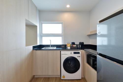 a kitchen with a washing machine and a sink at Centre Point Plus Hotel Pratunam in Bangkok