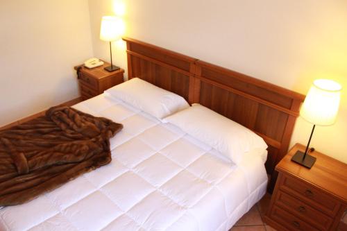 a bedroom with a large white bed with two lamps at Hotel Portici in Vicoforte