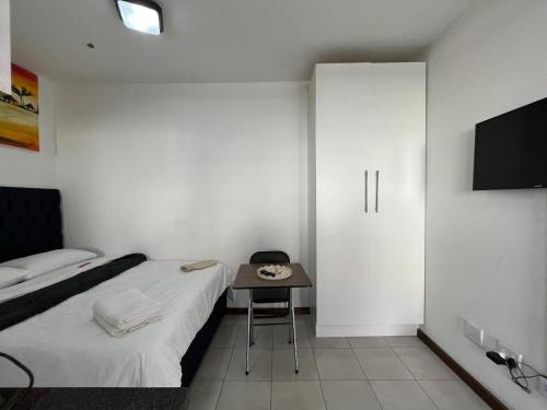a room with a bed and a table and a tv at The studios at Forest Glen in Johannesburg