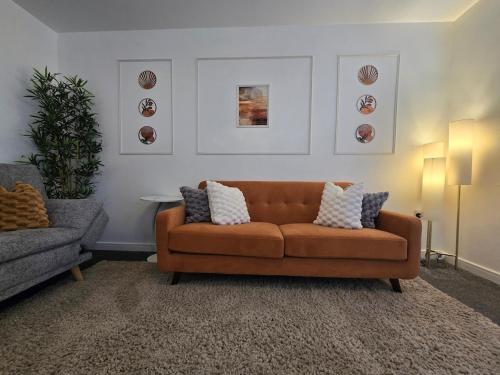 a living room with a brown couch and a chair at The Charm Luxury House - 8mins to NEC, Birmingham Airport in Marston Green
