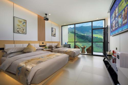 a bedroom with two beds and a large window at Enjoy the panoramic view of the rice fields (Longsheng Longji Terraces Branch) in Heping