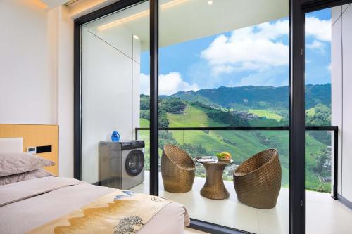 a bedroom with a large window with a table and chairs at Enjoy the panoramic view of the rice fields (Longsheng Longji Terraces Branch) in Heping