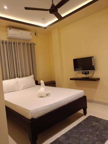 a bedroom with a bed and a flat screen tv at Muns Hotel in Bongaigaon