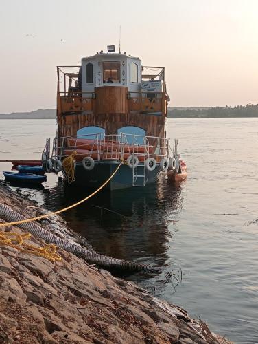 a boat is docked in the water next to the shore at Houseboat Hotel and Nile Cruises Zainoba in Nag` el-Ramla