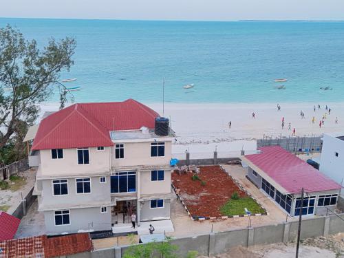 a white building with a red roof next to a beach at Spacious Beachfront Condo -AC - WiFi, Uroa Escape Zanzibar in Uroa