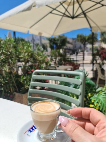 a person holding a cup of coffee on a table at Mare e Relax in Mola di Bari