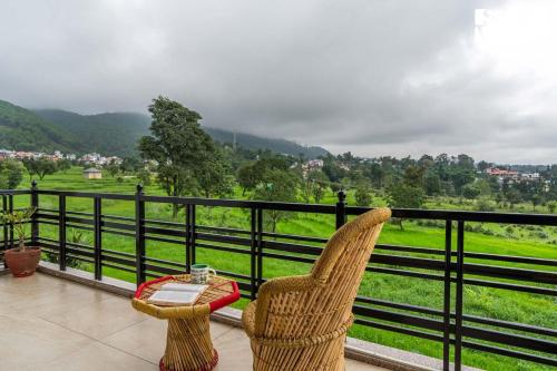 a chair and a table on a balcony with a view at Vaikunth Villa by VEO - Part of StayVista in Pālampur