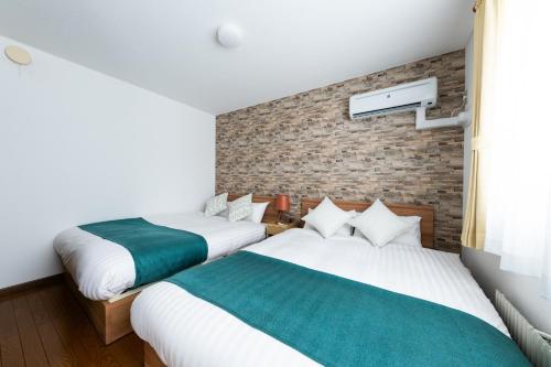 2 letti in una camera con muro di mattoni di Hongo Street House - Vacation STAY 8609 a Sapporo