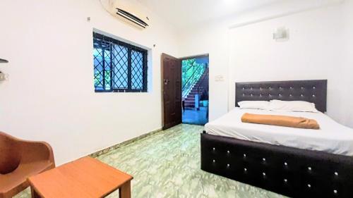 a bedroom with a bed and a table and a window at Baga Haven Guesthouse in Baga
