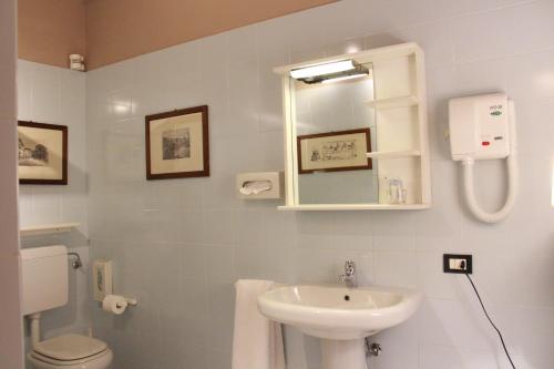 a bathroom with a sink and a toilet and a mirror at Hotel Portici in Vicoforte