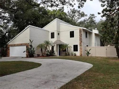a white house with a driveway in front of it at Pool Home at Busch Gardens USF in Tampa