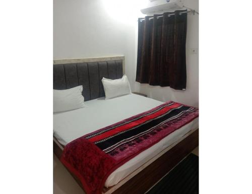 a bed with white sheets and a red blanket at Hotel Shiv Shakti, Chitrakoot in Chitrakoot