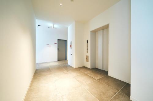 an empty hallway with white walls and tile floors at Rakuten STAY Osaka Station North Standard Fourth in Osaka