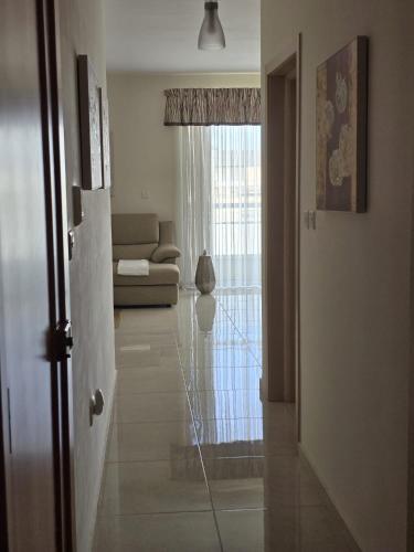 a living room with a couch and a glass door at Seabreeze Marsaxlokk Apartment in Marsaxlokk