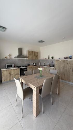 a kitchen with a wooden table and chairs at Seabreeze Marsaxlokk Apartment in Marsaxlokk