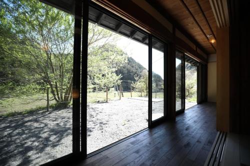 a room with a large window looking out at a yard at Cominka Hotel Shiki no Ie - Vacation STAY 89847 in Mitake