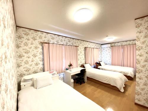 a room with two beds and a desk in it at Golf house - Vacation STAY 9043 in Ryūgasaki
