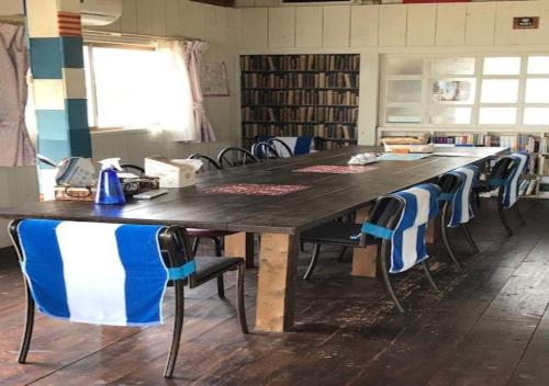 a large wooden table with chairs in a library at Guesthouse Yadokari - Vacation STAY 90101 in Imabari