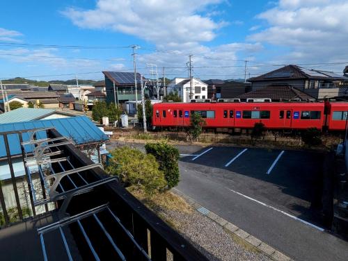 a red train is on the tracks next to a parking lot at guest house Ki-zu - Vacation STAY 94978v in Nishio