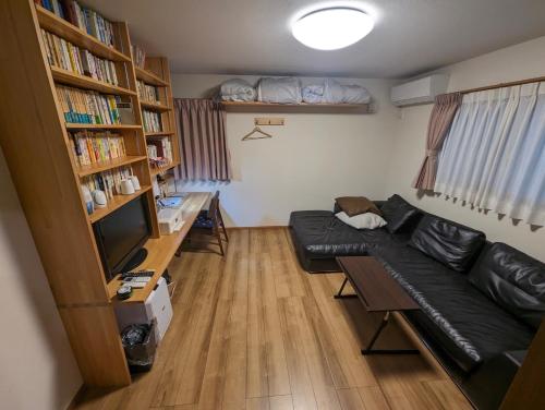 a living room with a couch and a table and book shelves at guest house Ki-zu - Vacation STAY 94978v in Nishio