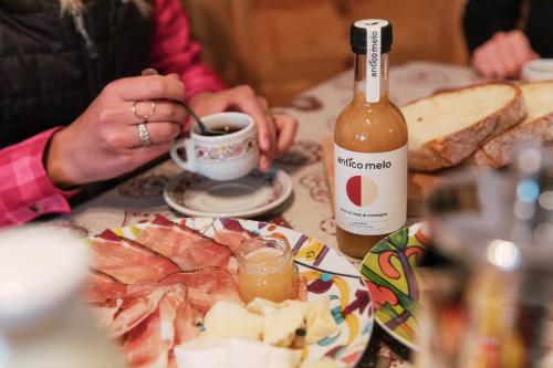 a person sitting at a table with a bottle of wine at Dolomitihouse ZIRMOL in Fiera di Primiero