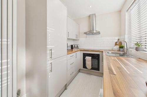 a kitchen with white cabinets and a sink at Host & Stay - Jomor House in Burnhope