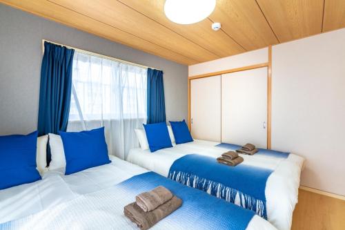 Dos camas en una habitación con azul y blanco. en ASAHI HOUSE 2nd floor - Vacation STAY 92770, en Naha