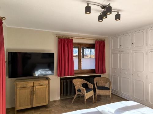 a bedroom with a flat screen tv and red curtains at Haus Blindauer Eck in Reit im Winkl