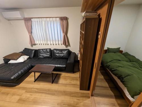 a living room with a black couch and a bed at guest house Ki-zu - Vacation STAY 96116v in Nishio
