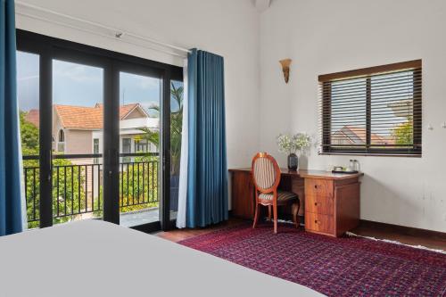 a bedroom with a bed and a desk and a window at Sila Ananda 6BR Pool Villa Đảo Xanh Đà Nẵng in Da Nang