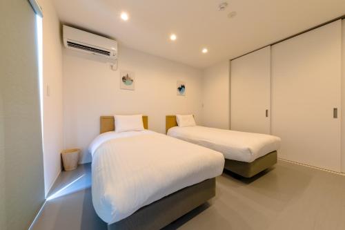 two beds in a room with white walls at Frame view -east- - Vacation STAY 94084 in Azagawa