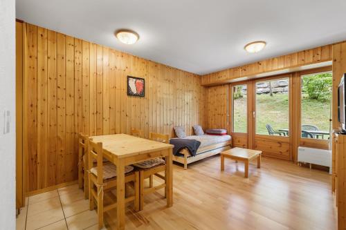 a room with wooden walls and a table and a bed at Charmant 2,5 pièces au pied des Bains d'Ovronnaz in Ovronnaz