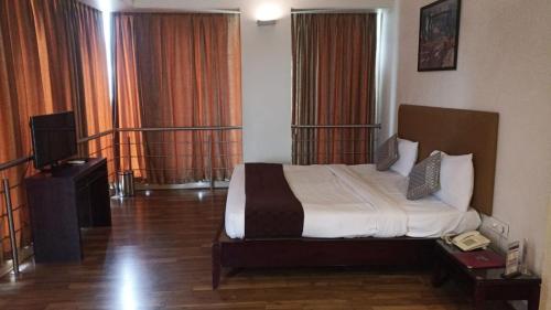 a hotel room with a bed and a television at Hotel Chaitali - Pure Veg in Kolhapur