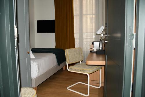 a bedroom with a bed and a desk and a chair at Hôtel Casimir in Paris