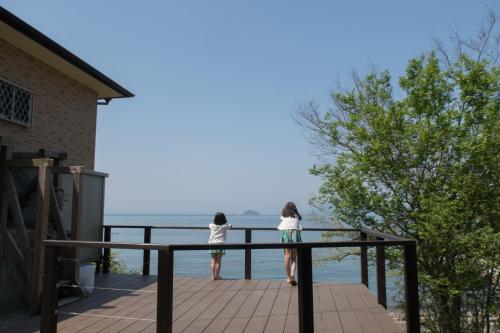 two children standing on a deck looking at the water at Villa Chillon - Vacation STAY 97710 in Sakate